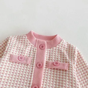 Pink houndstooth knit cardigan detail, infant baby girl clothing closeup view texture shot.