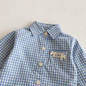 Primo piano dettagliato della camicia a maniche lunghe a quadri blu e bianchi da bambina.