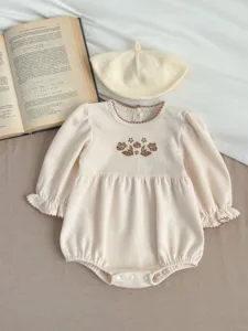 Detailed view of baby girl waffle knit romper with floral embroidery and matching beret hat.