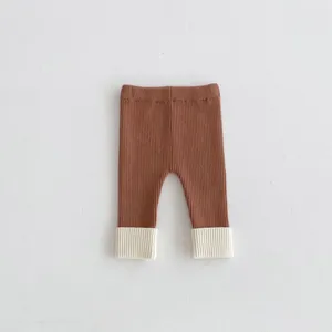 Primo piano dettaglio di leggings in maglia per neonati con corpo marrone e polsini.