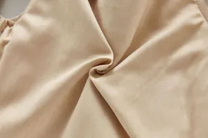 Kids winter vest fabric detail view showing soft beige texture close up studio macro shot