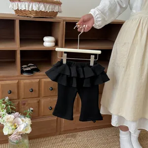 Infant girls black flare pants detail view, ruffles fake two piece skirt design.