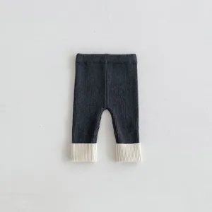 Primo piano di leggings in maglia per neonati, tessuto a costine e risvolti a contrasto.