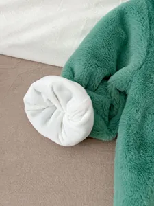 Dettaglio tutina pile neonato, tessuto verde morbido con calda fodera interna.