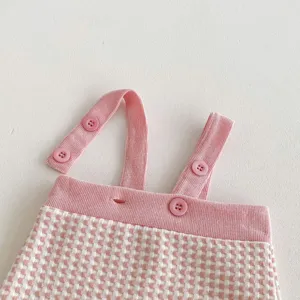 Pink and white checkered knit baby overalls detail, cute style, soft textured fabric with buttons.