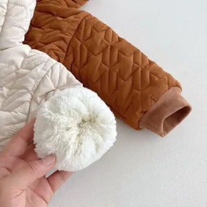 Details van winter katoenen babyjas met gewatteerde textuur, fleece en pluche pompon.