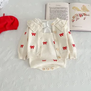 Close-up detail of infant knit cardigan and romper set with sweet red bows and elegant collar.