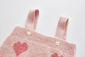 Close-up detail of pink baby knit romper featuring cute fuzzy heart patterns and buttons.