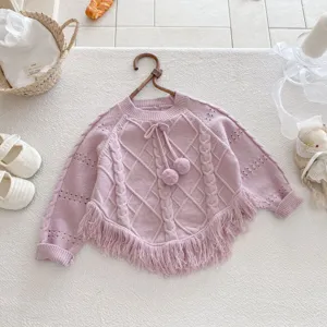 Detailed view of kids knit sweater with fringe hem, jacquard pattern and cute pom poms.