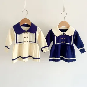 Detailed view of baby girls knit sailor dress showing contrast color collar and pleated skirt.