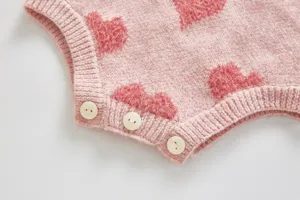 Baby pink knit romper detail view, cute fuzzy heart pattern with buttons for infant wear.