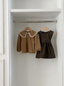 Detailed shot of infant toddler girls spring outfit, brown lace collar top and plaid dress.