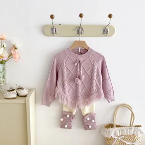 Close-up detail of a cute toddler pink knit sweater poncho with tassels and matching leggings.