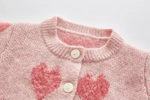 Detail shot of pink baby knit cardigan collar and buttons with fuzzy heart pattern, soft and cute.