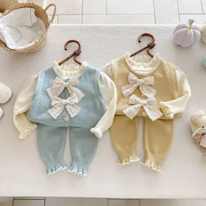 Primo piano dei dettagli in maglia con fiocchi graziosi per questo accogliente completo bimba.