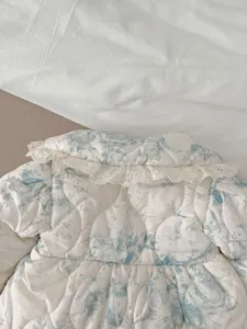 Baby winter quilted jacket detail, featuring soft blue print and cute white lace collar.