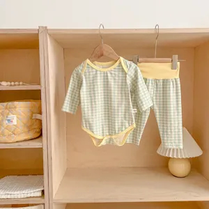 Dettaglio body e pantaloni a quadri in cotone bimbo, presentazione su scaffale in legno.