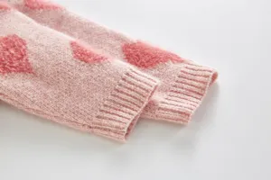 Infant baby knitted winter clothes detail, pink fuzzy heart pattern, soft ribbed cuffs.