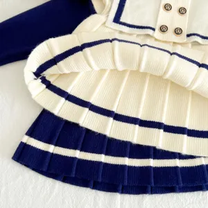 Close-up detail of toddler girls sailor style knit dress, pleated skirt and navy contrast.