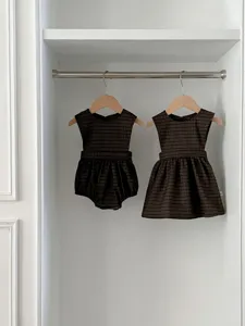 Infant baby girl matching plaid sleeveless romper and dress set detail view in neutral setting