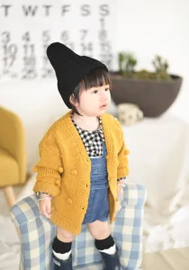 Gedetailleerd overzicht van gebreid vest voor babymeisje, schattige handgemaakte pompon peuterjas.