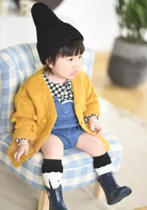 Detail gebreid babyvest, handgemaakte nopjes trui voor kleine meisjes, gezellige herfstmode.