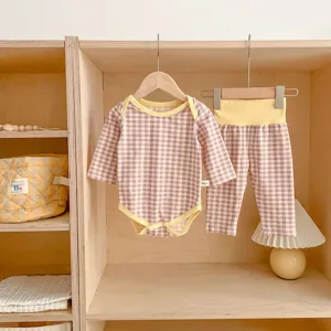 Vista dettagliata del set body e pantaloni a quadri in cotone per neonati su ripiano in legno.