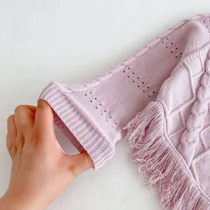 Close-up detail of girls knitted sweater cuff, cable knit texture, soft purple fabric