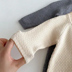 Close-up of knit baby romper sleeve detail, soft texture, comfortable autumn infant clothing.