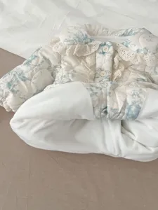 Detailed view of baby quilted warm outerwear featuring a delicate floral print and lace collar.