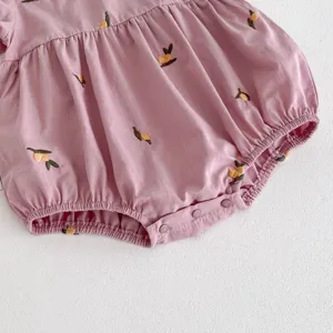 Primer plano de mameluco morado para bebé niña con bordado de limón lindo y prácticos botones.