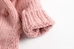 Detail van gebreid babyvestje voor meisjes, roze wollen trui manchet met zachte pompon.