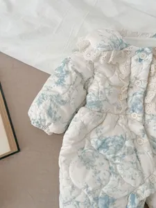 Detailed shot of baby winter warm quilted coat with cute lace collar and blue floral print.