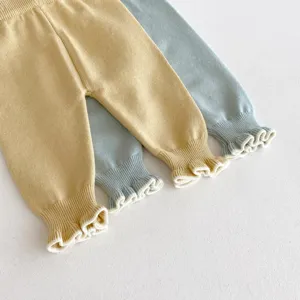 Vista dettagliata di leggings in maglia per neonati con graziosi polsini con volant gialli e blu.