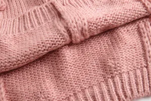 Close-up van roze gebreide babyvest stof, met zachte garentextuur en schattig patroon.