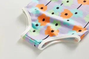 Child swimsuit floral detail, purple background with colorful poppy print and white trim.