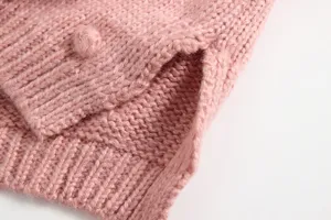 Detail van gebreid babymeisjesvest, roze wollen trui stof met handgemaakte pompon top.