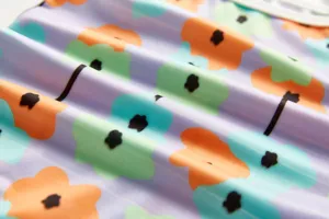 Children one-piece swimsuit fabric detail close-up with colorful floral print design.