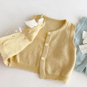 Dettaglio gilet lavorato a maglia per neonata con pizzo e bottoni, morbido top invernale per bimbi.