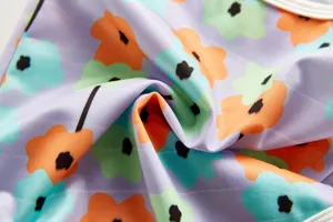 Close up fabric detail of children floral print one piece swimsuit with vibrant colorful pattern.