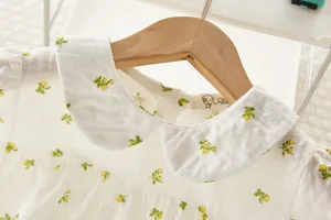 Detalle de cuello de blusa floral blanca de bebé, vista cercana de camisa de infante