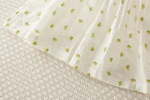 Detalle de tela floral de vestido de verano para bebé con flores amarillas y blancas.