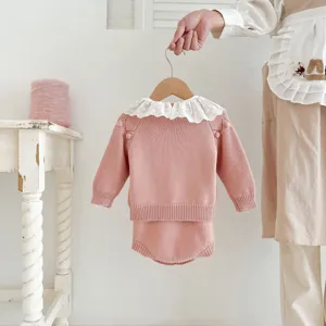 Close-up detail of infant pink knit sweater set featuring delicate white lace collar for babies.