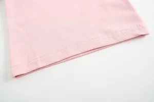 Dettaglio orlo top in cotone per neonata rosa, tessuto morbido e cuciture pulite.