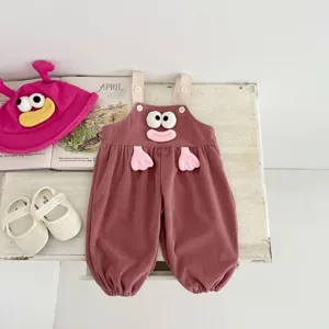 Detailed shot of cute baby corduroy overalls set in pink with funny doll design and props.