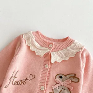Roze baby gebreid vest detailweergave met witte kanten kraag en schattige konijn borduurwerk.
