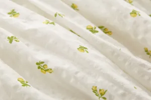 Primer plano del tejido de algodón suave con textura de estampado floral amarillo delicado.
