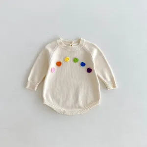 Vue détaillée de la barboteuse pour bébé en tricot avec des fleurs crochetées sur la poitrine.