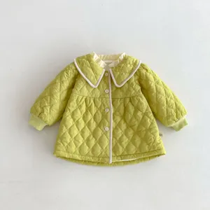 Detailed view of kids quilted coat featuring doll collar, green pattern and button closure.