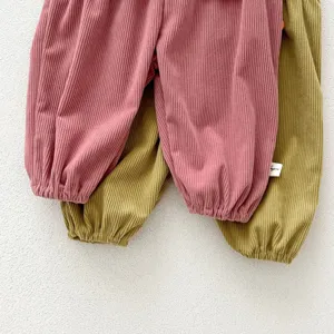 Infant corduroy pants detail close-up, soft ribbed fabric, cute baby trousers in pink and green